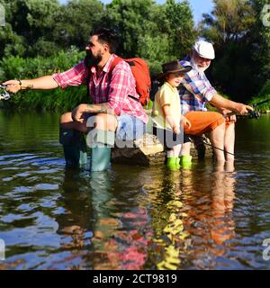 Buon giorno dei padri. Padre insegnando al figlio come pescare a mosca nel fiume. Nonno e nipote sono pesca a mosca sul fiume. Hobby uomo. Giorno d'estate. Foto Stock