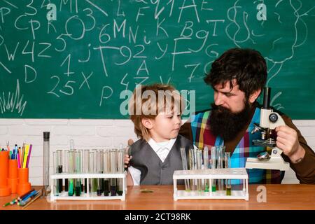 Esperimenti di biologia al microscopio. Buona famiglia. Genitorialità. Giorno della conoscenza. Ragazzo che fa il suo lavoro scolastico con suo padre. Ritorno a scuola Foto Stock