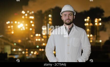 L'ingegnere raddrizza i vestiti e guarda la macchina fotografica in piedi da olio Foto Stock