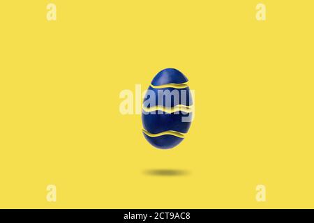 Uovo di pasqua tagliato in volo su sfondo giallo, l'uovo è giallo all'interno. Concetto di hipster minimo. Foto Stock