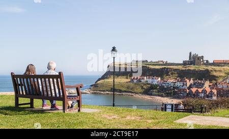 Una coppia anziana ha visto sedersi su una panchina che si affaccia sul porto di Whitby nello Yorkshire nel settembre 2020. Foto Stock