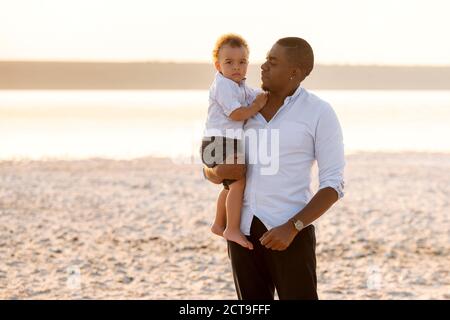 Ritratto del giovane padre e del figlio del bambino serio. Bambino sulle mani del padre Foto Stock