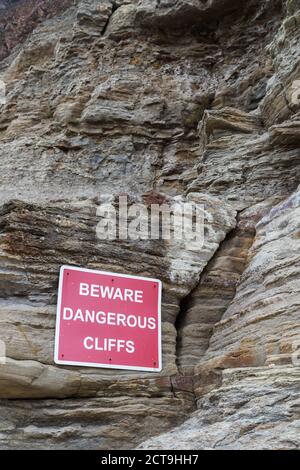 Simbolo di avvertimento delle scogliere pericolose raffigurato ai piedi del Scogliere che proteggono il villaggio di Staithes sul North Yorkshire Costa visto nel settembre 202 Foto Stock