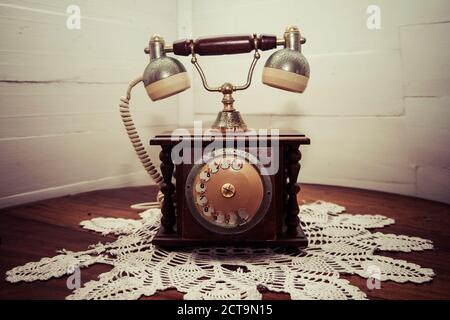 Il vecchio telefono in piedi sulla tovaglia a crochet in un angolo Foto Stock