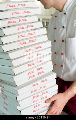 Uomo che porta pila di scatole per pizza Foto Stock