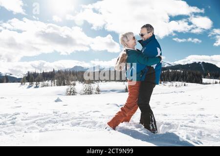 In Germania, in Baviera, Winklmoosalm, Coppia matura abbracciando nella neve Foto Stock