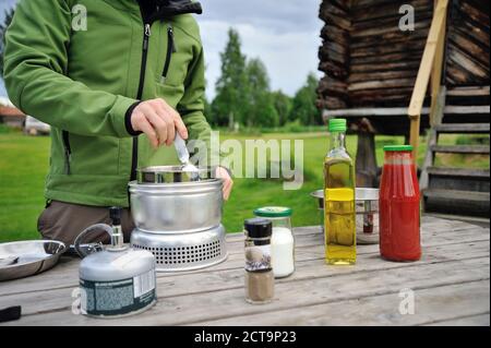 La Svezia, Leksand, l'uomo la cottura della pasta sul fornello da campeggio Foto Stock