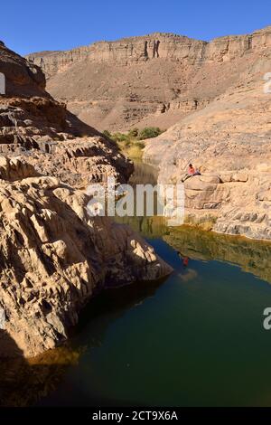 Africa, Algeria, del Tassili N'Ajjer National Park, Iherir, Donna in appoggio in prossimità di acqua in una guelta, Idaran Canyon Foto Stock