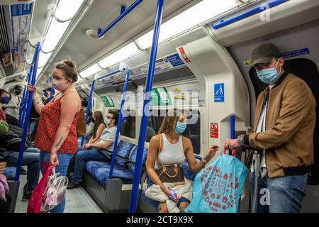 I pendolari indossano maschere per proteggere la diffusione del coronavirus che viaggia sulla metropolitana di Londra, Inghilterra, Regno Unito Foto Stock