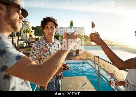 Gli amici a bere una birra su highboard di una piscina Foto Stock