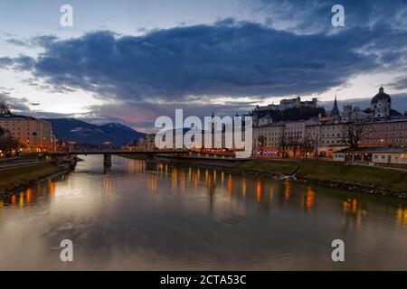 Austria, Salisburgo, Salisburgo, la fortezza di Hohensalzburg con la città vecchia e le torri della cattedrale di Salisburgo, il fiume Salzach, la chiesa collegiata destra, in serata Foto Stock