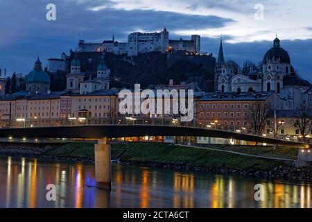 Austria, Salisburgo, Salisburgo, la fortezza di Hohensalzburg con la città vecchia e le torri della cattedrale di Salisburgo, il fiume Salzach, la chiesa collegiata destra, in serata Foto Stock