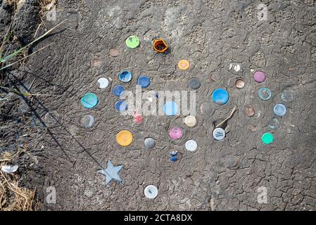 Le parti superiori delle bottiglie di plastica sono spinte nello strato di catrame del muro di mare a Chalkwell, Southend on Sea, Essex, UK. Cinder percorso sull'estuario del Tamigi con tappi per bottiglia Foto Stock