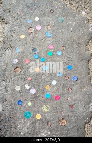 Le parti superiori delle bottiglie di plastica sono spinte nello strato di catrame del muro di mare a Chalkwell, Southend on Sea, Essex, UK. Cinder percorso sull'estuario del Tamigi con tappi per bottiglia Foto Stock