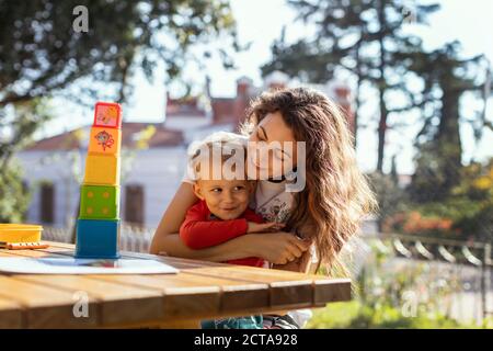 Madre e figlio si coccolano e giocano con i giocattoli Educational Cube Nel Giardino Foto Stock