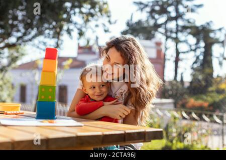 Madre e figlio si coccolano e giocano con i giocattoli Educational Cube Nel Giardino Foto Stock