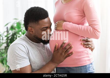 Primo piano di un uomo nero che bacia il ventre della moglie incinta Foto Stock