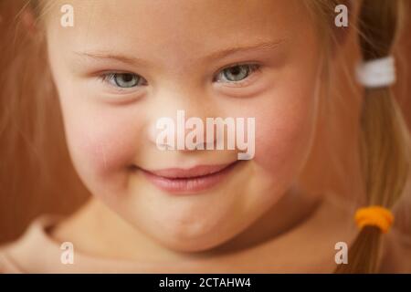 Primo piano ritratto di carina ragazza con sindrome giù sorridente a macchina fotografica felicemente, studio girato Foto Stock