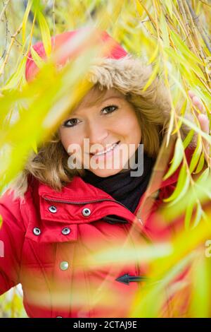 Ritratto di una donna bionda tra le foglie di a. salice piangente Foto Stock