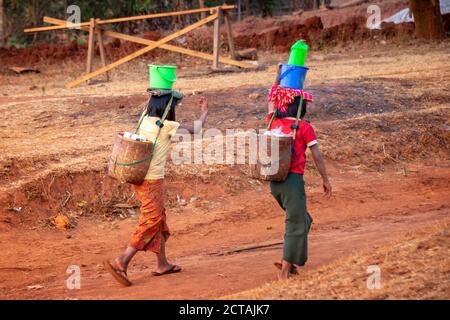 Due ragazze che prelevano acqua con secchi di plastica e lattine in Birmania, Myanmar Foto Stock