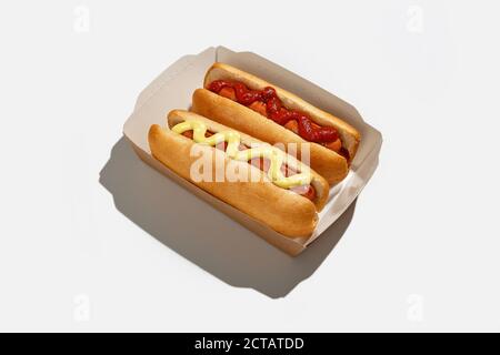 Consegna rapida degli alimenti in confezioni eco-cartacee per i clienti a casa durante la pandemia di covid-19. Due hot dog con salsiccia alla griglia con ketchup e senape Foto Stock