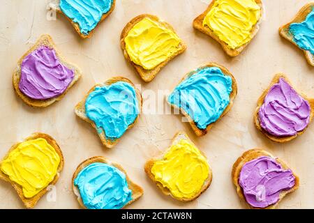 Divertente pane tostato con formaggio colorato spalmato. Vista dall'alto Foto Stock