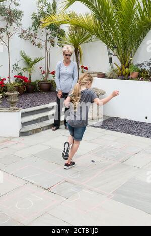 Una nonna insegna a sua nipote un gioco tradizionale di hopscotch. Foto Stock