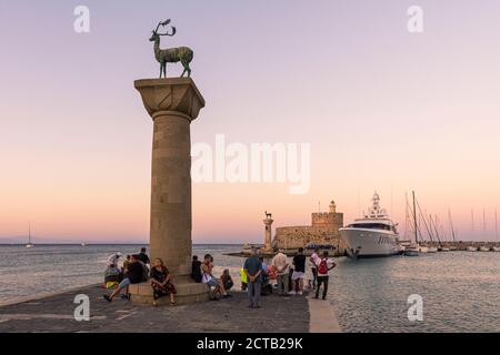 Tramonto sulle statue di bronzo dei cervi e sulla Fortezza di San Nicola all'ingresso del porto di Mandraki, della città di Rodi, dell'isola di Rodi, della Grecia Foto Stock