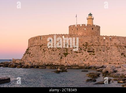 Tramonto sulla Fortezza di San Nicola, il porto di Mandraki, la città di Rodi, l'isola di Rodi, la Grecia Foto Stock