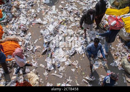 Kolkata, India - 2 febbraio 2020: Le persone non identificate camminano attraverso il giornale dei rifiuti al mercato dei fiori di Mallick Ghat al ponte Howrah Foto Stock