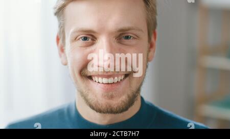 Ritratto di bell'uomo giovane biondo sorridente, mentre si guarda la fotocamera. Felice attraente Guy con gli occhi blu Foto Stock