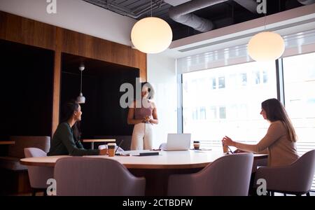Tre Businesswomen che hanno socialmente distanziato riunione in ufficio durante la salute Pandemia Foto Stock