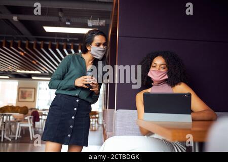 Uomini d'affari che indossano maschere avendo socialmente distanziato riunione in ufficio durante Pandemic di salute Foto Stock