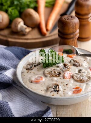 Ciotola di crema di zuppa di funghi su rustico tavolo di legno con ingredienti in background Foto Stock