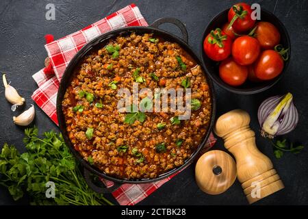 sause bolognese in piastra di ferro a tavola nera. Foto Stock