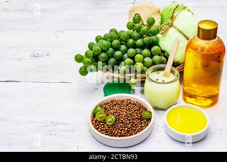 Accessori termali naturali e uva verde. Ingredienti freschi per una cura di sé sana e confortevole. Sfondo bianco tavole di legno, spazio copia Foto Stock