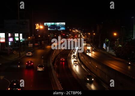 Phuket, Thailandia - 26 febbraio 2018: Città notturna e strada. Auto e motociclisti che guidano su un'autostrada buia, vista dall'alto Foto Stock
