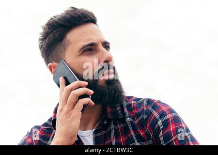 ritratto di un bell'uomo bearded che parla dal telefono cellulare, concetto di libertà e tecnologia, spazio di copia per il testo Foto Stock
