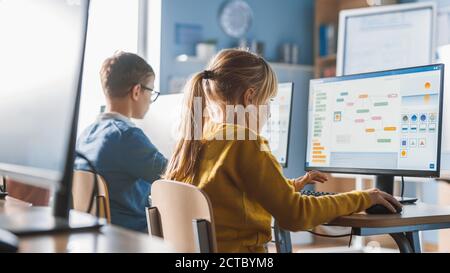 Scuola elementare computer Science Classroom: Cute Little Girl utilizza Personal computer, apprendimento linguaggio di programmazione per la codifica software Foto Stock