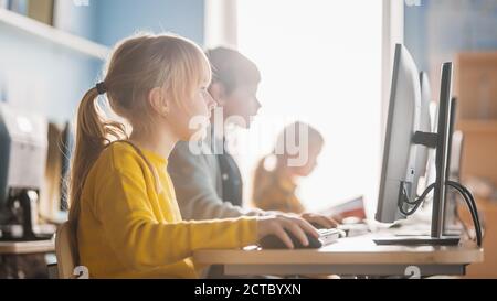 Scuola elementare computer Science Classroom: Ritratto di una smart cute Girl utilizza Personal computer, Informatica didattica, sicurezza Internet, programmazione Foto Stock