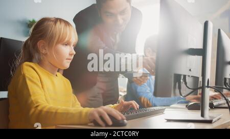 Scuola elementare Scienza aula: Insegnante spiega a una piccola scuola intelligente come usare Personal computer, per imparare linguaggio di programmazione necessario Foto Stock