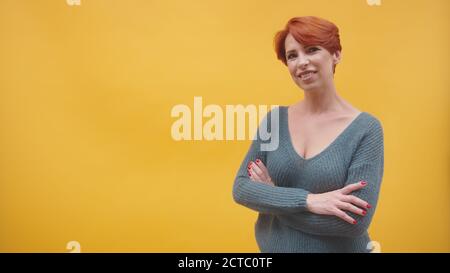 Ritratto di donna di mezza età rossa con mani accovacciate che sbricchiolano, isolato su sfondo arancione. Foto di alta qualità Foto Stock
