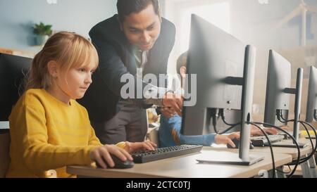 Scuola elementare Scienza aula: Insegnante spiega a una piccola scuola intelligente come usare Personal computer, per imparare linguaggio di programmazione necessario Foto Stock