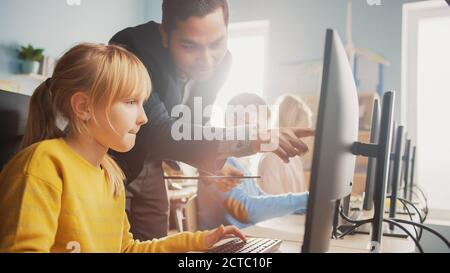 Scuola elementare Scienza aula: Insegnante spiega a una piccola scuola intelligente come usare Personal computer, per imparare linguaggio di programmazione necessario Foto Stock