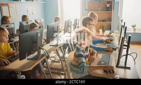 Scuola elementare Informatica Classroom: Gruppo diversificato di piccoli studenti intelligenti che utilizzano Personal computer, imparare Informatica, Internet Foto Stock