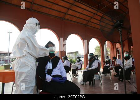 Surabaya, Indonesia. 22 settembre 2020. Un lavoratore medico che indossa tuta protettiva raccoglie campioni di tampone da una donna prima di un esame per un dipendente civile statale a Surabaya, Indonesia, 22 settembre 2020. I casi COVID-19 in Indonesia sono saliti di 4,071 in un giorno a 252,923, con il numero di morti che si aggiunge da 160 a 9,837, ha detto il ministero della salute martedì. Credit: Kurniawan/Xinhua/Alamy Live News Foto Stock