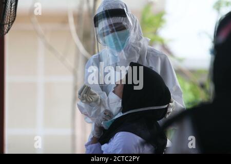 Surabaya, Indonesia. 22 settembre 2020. Un lavoratore medico che indossa tuta protettiva raccoglie campioni di tampone da una donna prima di un esame per un dipendente civile statale a Surabaya, Indonesia, 22 settembre 2020. I casi COVID-19 in Indonesia sono saliti di 4,071 in un giorno a 252,923, con il numero di morti che si aggiunge da 160 a 9,837, ha detto il ministero della salute martedì. Credit: Kurniawan/Xinhua/Alamy Live News Foto Stock
