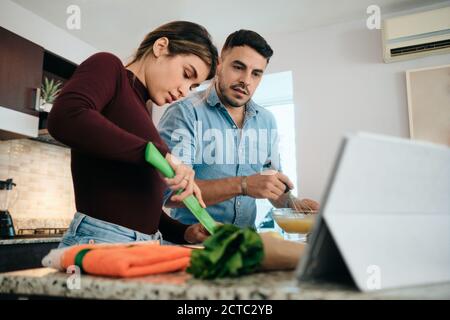 Cucina di coppia insieme guardando Tutorial per la ricetta Foto Stock