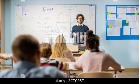 Foto di insegnante che spiega la lezione in aula piena di diversi Bright Children, nel gruppo scolastico elementare di Smart multietnica Bambini Learning Science Foto Stock