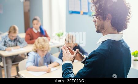 Sopra il colpo dell'anima dell'insegnante che spiega la lezione alla classe piena dei bambini luminosi differenti, nel gruppo della scuola elementare dei capretti multietnici intelligenti Foto Stock